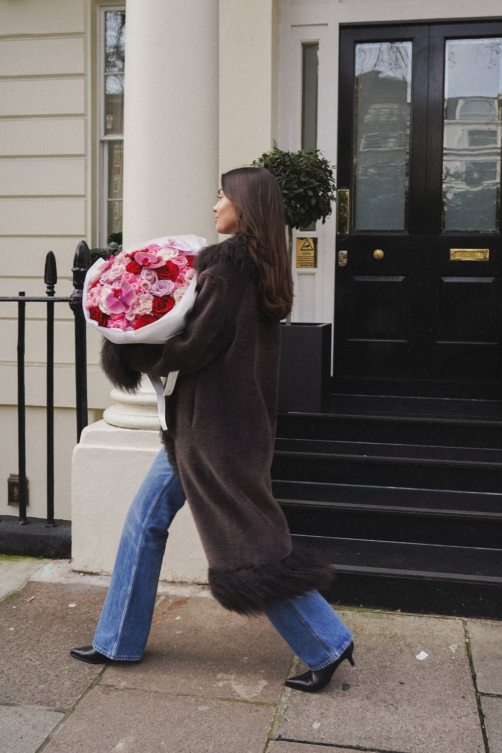 woman holding luxury red roses and orchids bouquet in knightsbridge